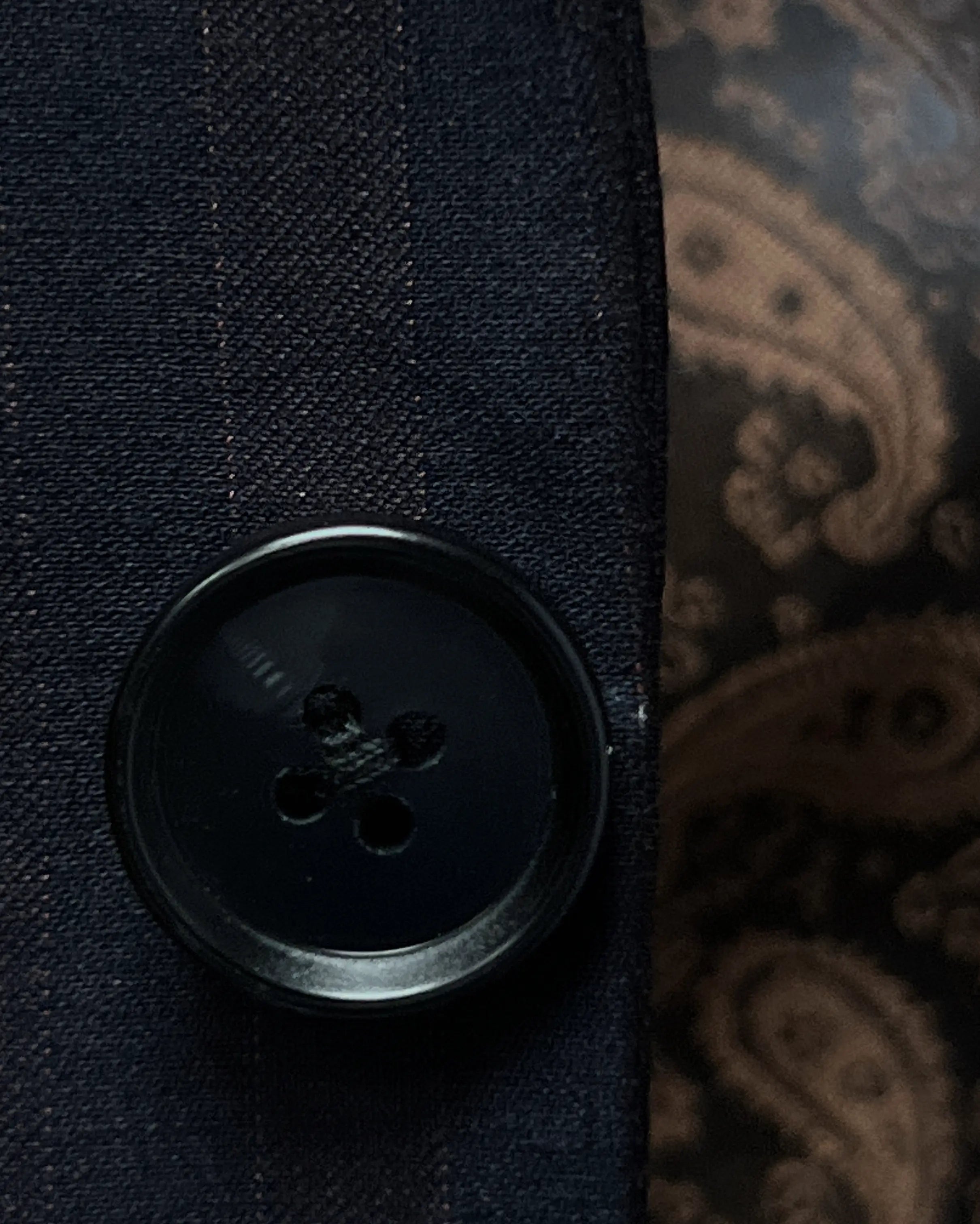 Button detail of dark navy with brown herringbone stripe men's suit showing black horn buttons.