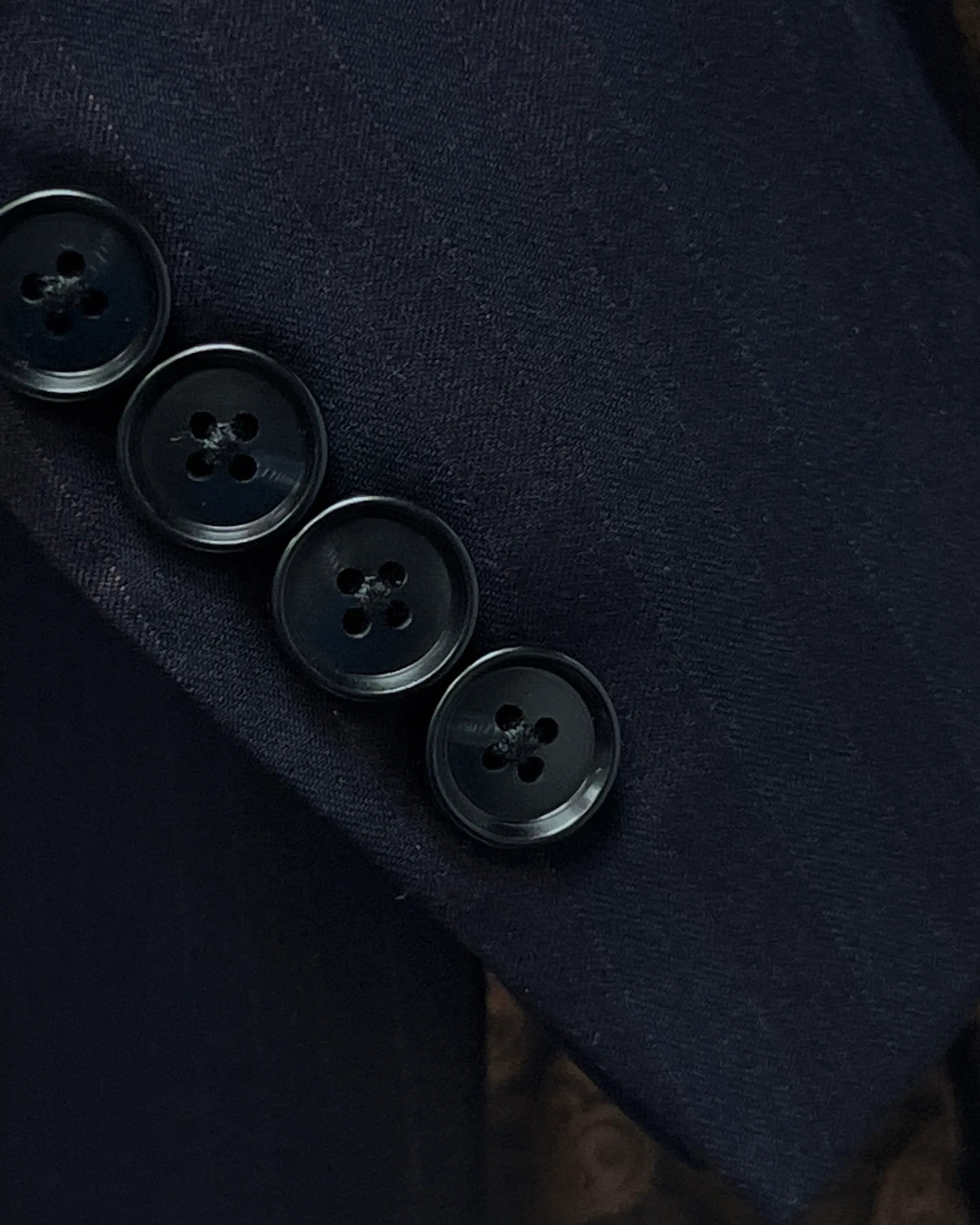 Sleeve cuff detail of dark navy with brown herringbone stripe men's suit showing functional sleeve buttons.
