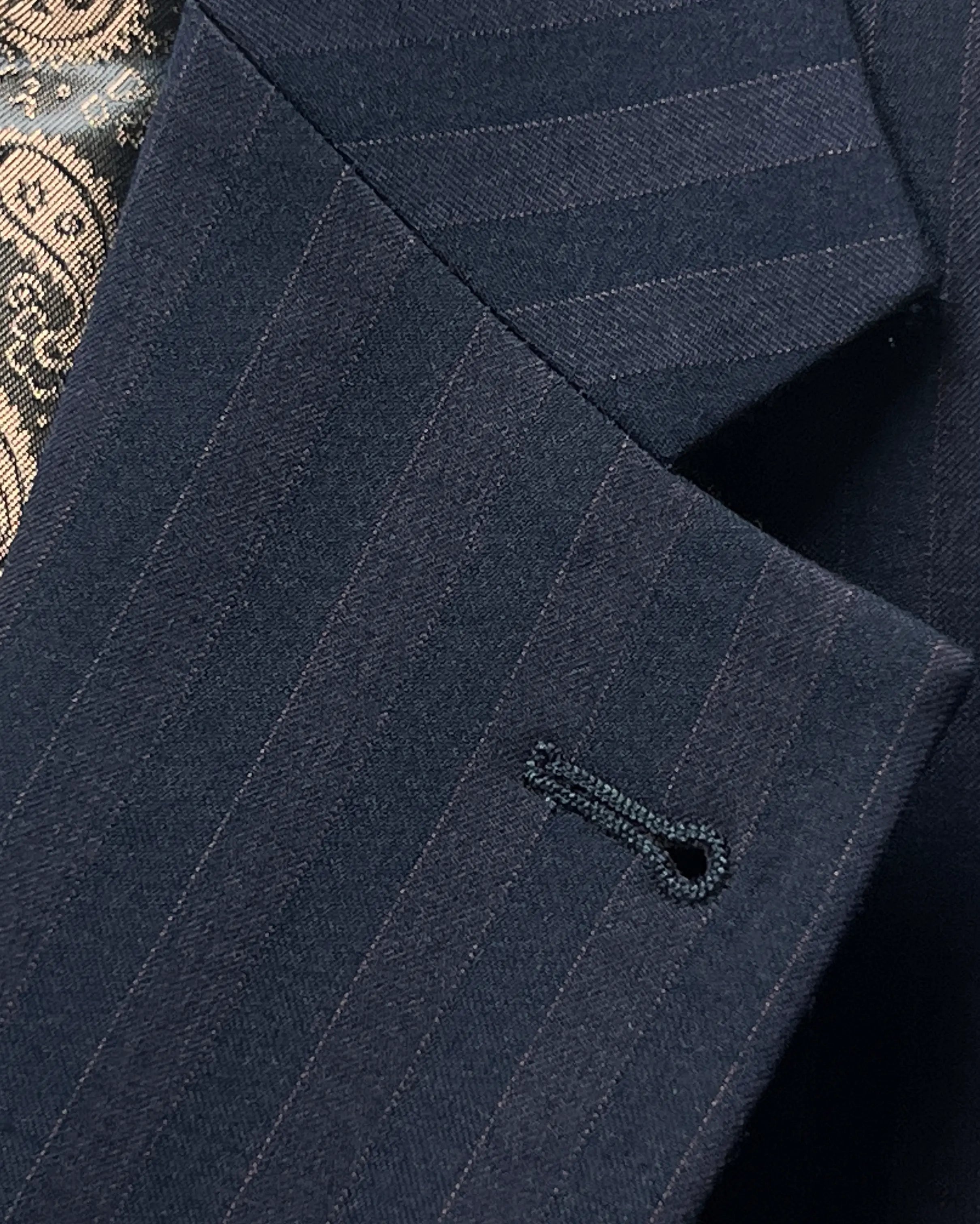 Lapel buttonhole detail of dark navy with brown herringbone stripe men's suit showing standard buttonhole stitching.