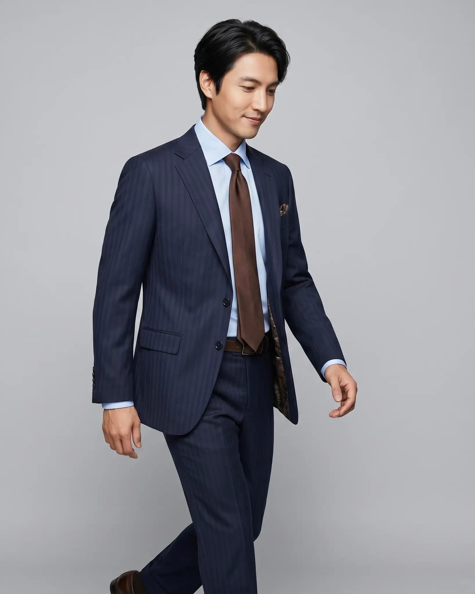 Mid length model image of dark navy with brown herringbone stripe men's suit showing the jacket drape and lining glimpse.