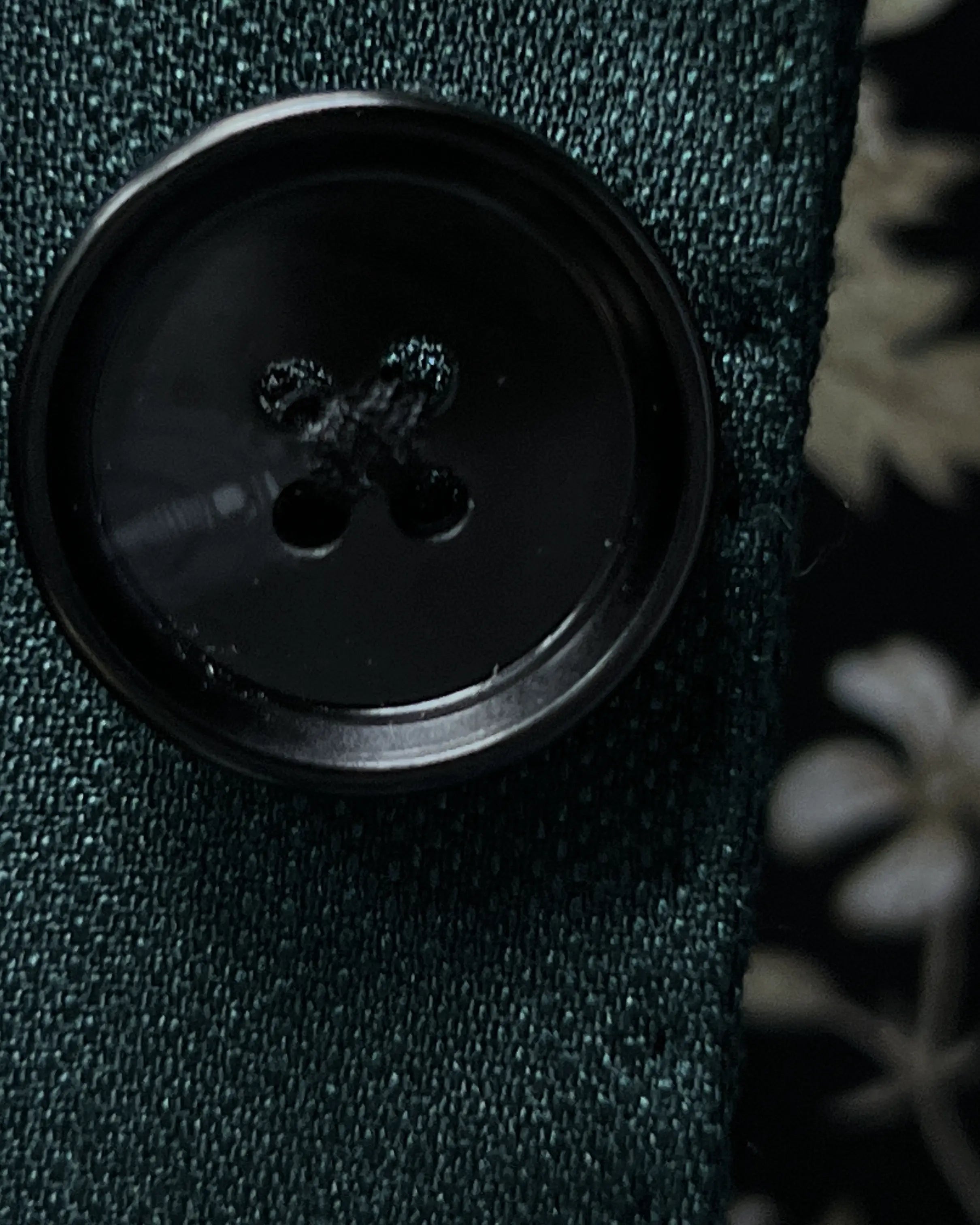 Button detail of deep teal green solid men's suit showing black horn buttons