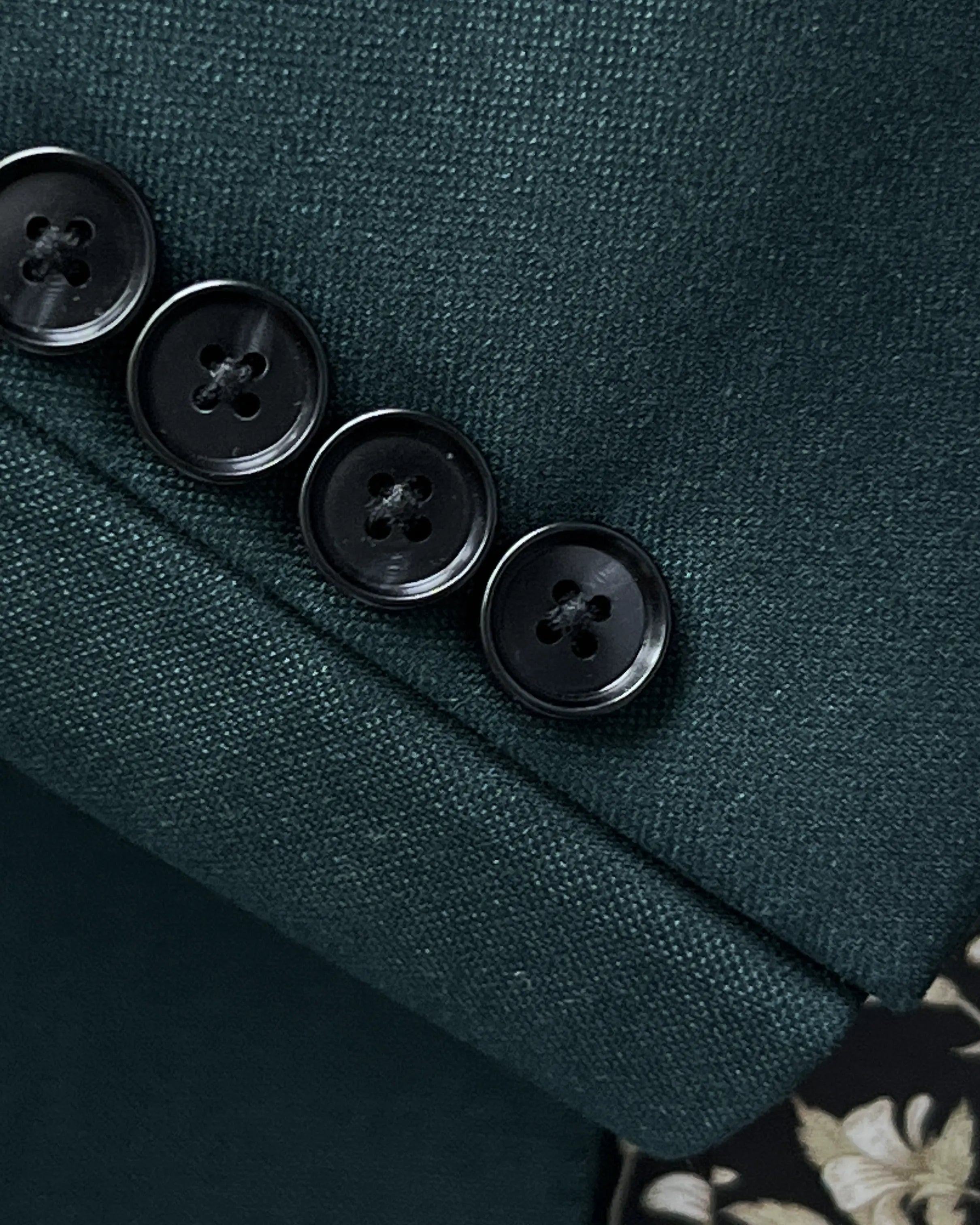 Functional sleeve button detail of deep teal green solid men's suit showing black horn cuff buttons and standard sleeve buttonholes