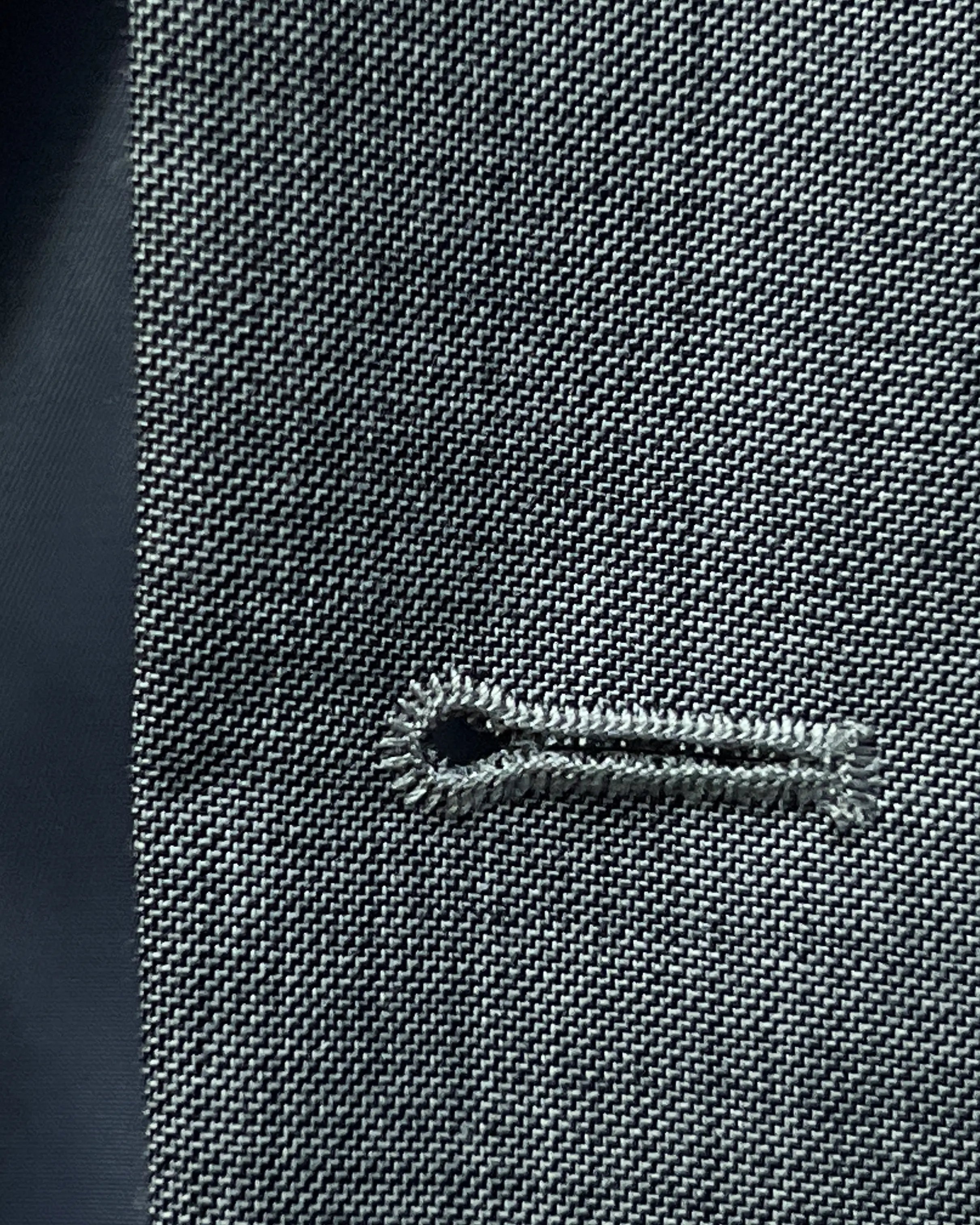 Buttonhole close up of grey sharkskin men's suit showing standard buttonhole stitching