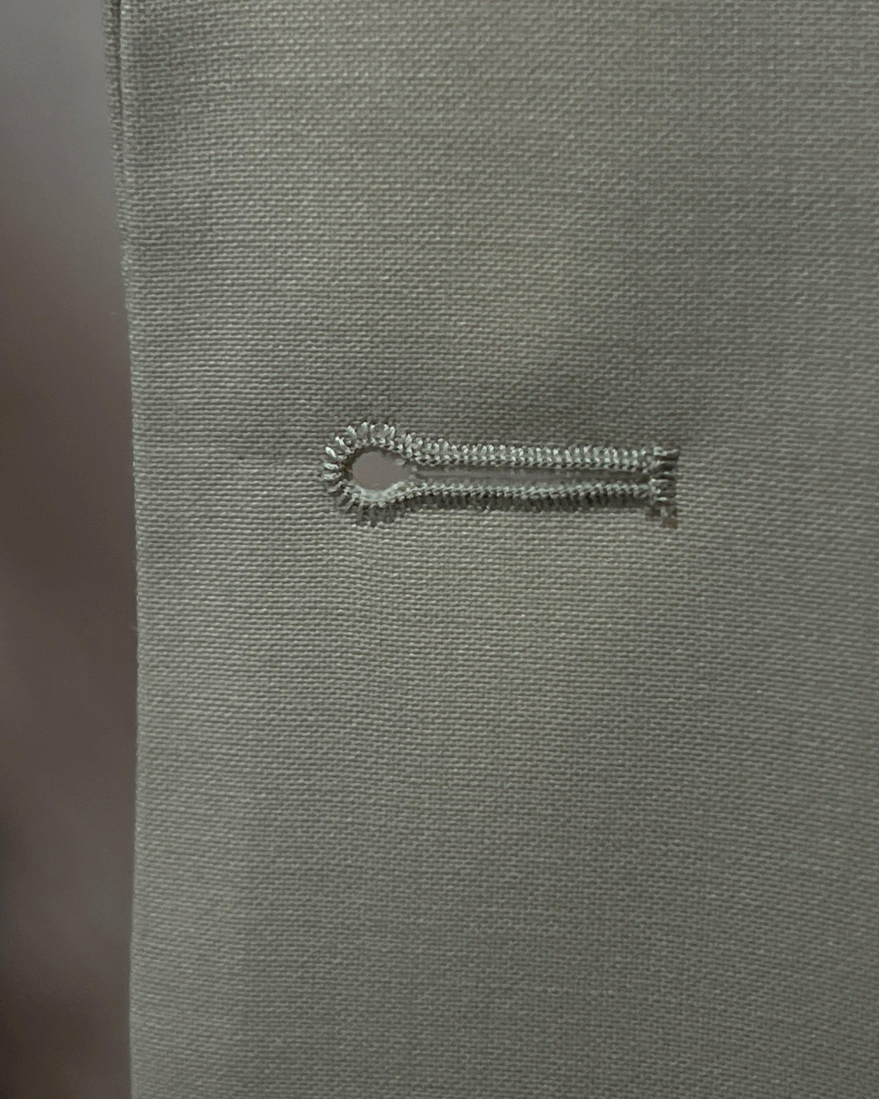 Buttonhole close up of light beige plain men's suit showing standard buttonhole stitching