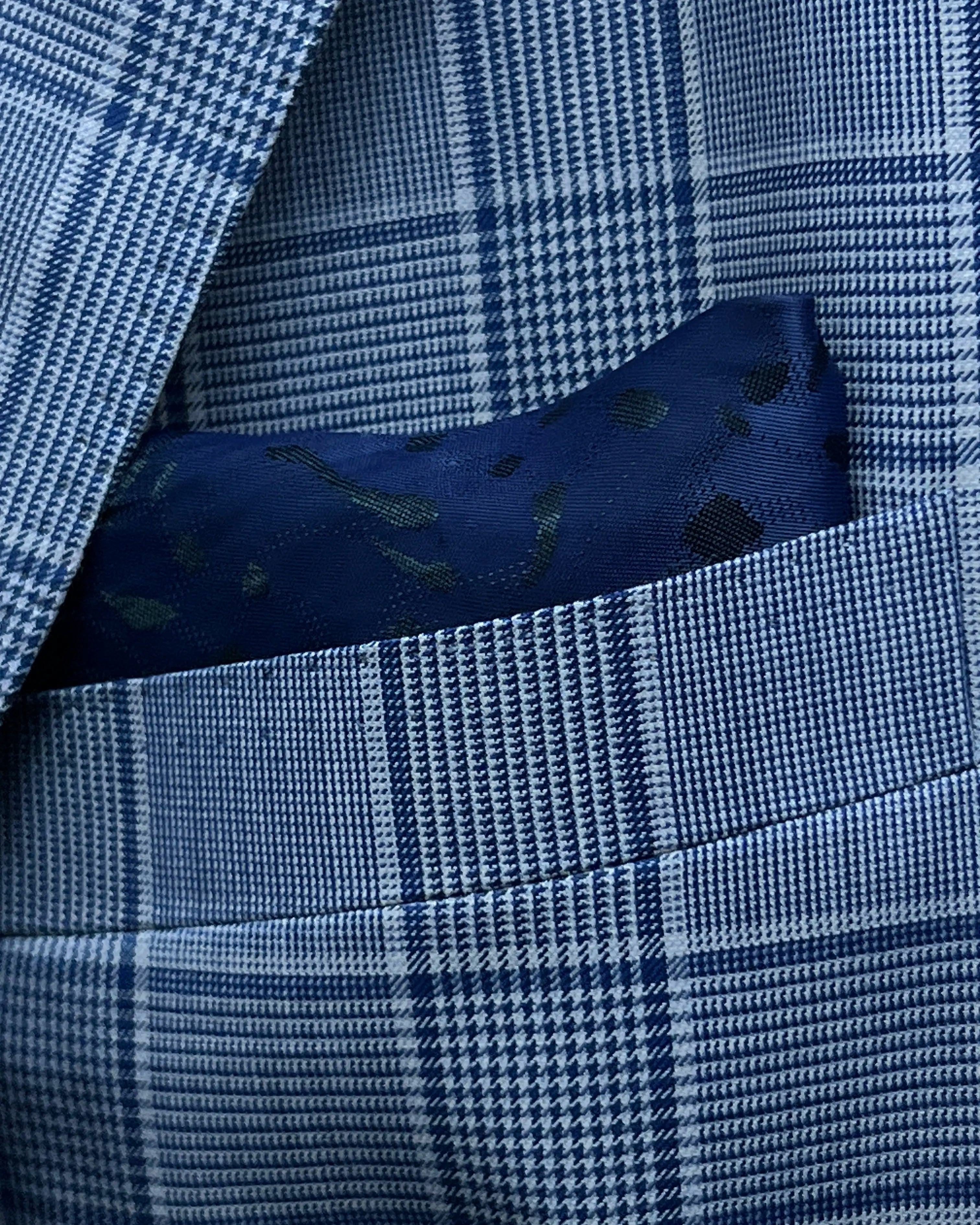 Pocket square close up of light blue Prince of Wales glen plaid with navy windowpane men's suit showing built in lining pocket square