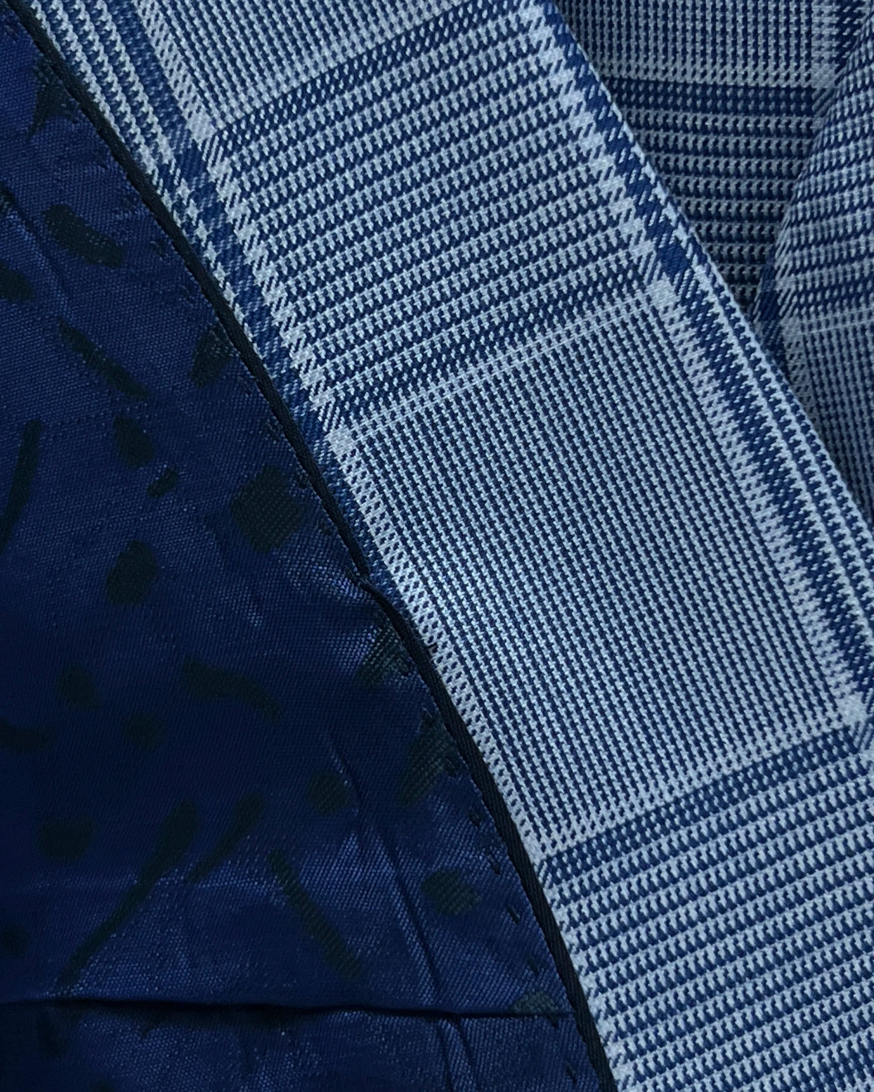 Fabric close up of light blue Prince of Wales glen plaid with navy windowpane men's suit showing smooth worsted texture and fine weave definition