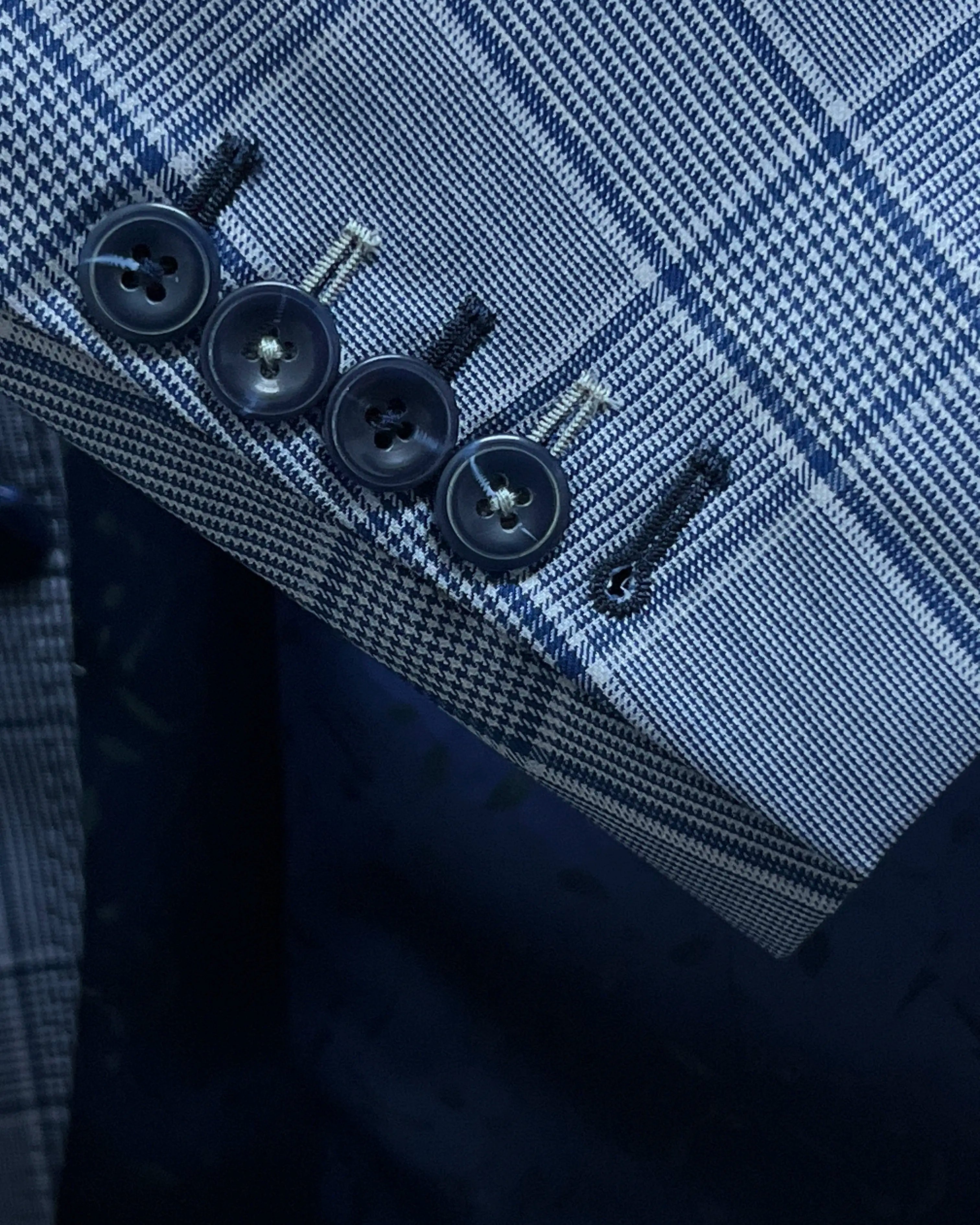Sleeve cuff close up of light blue Prince of Wales glen plaid with navy windowpane men's suit showing functional sleeve buttons and navy grey alternating contrast buttonhole
