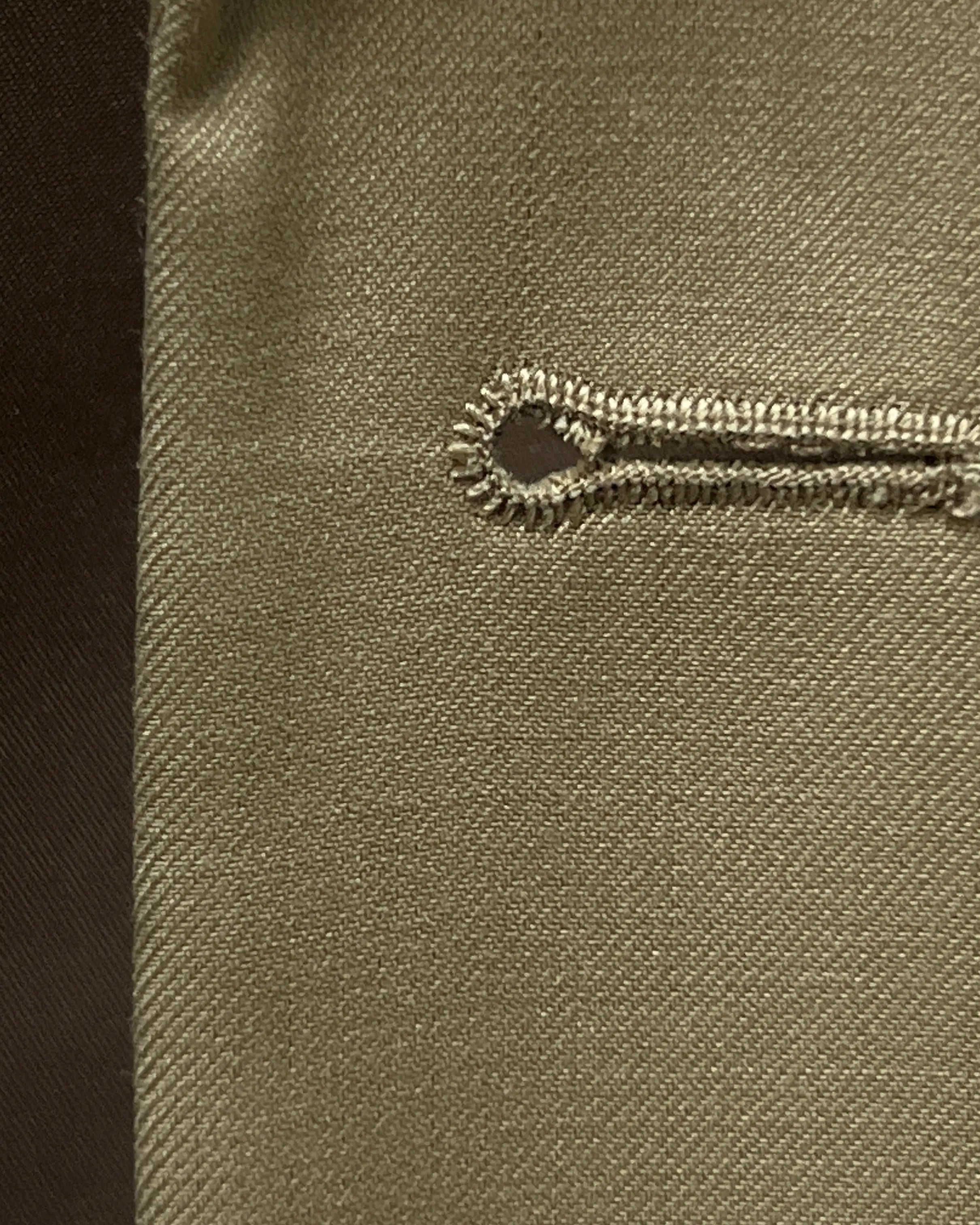 Buttonhole close up of brown plain men's suit showing clean functional buttonhole detail