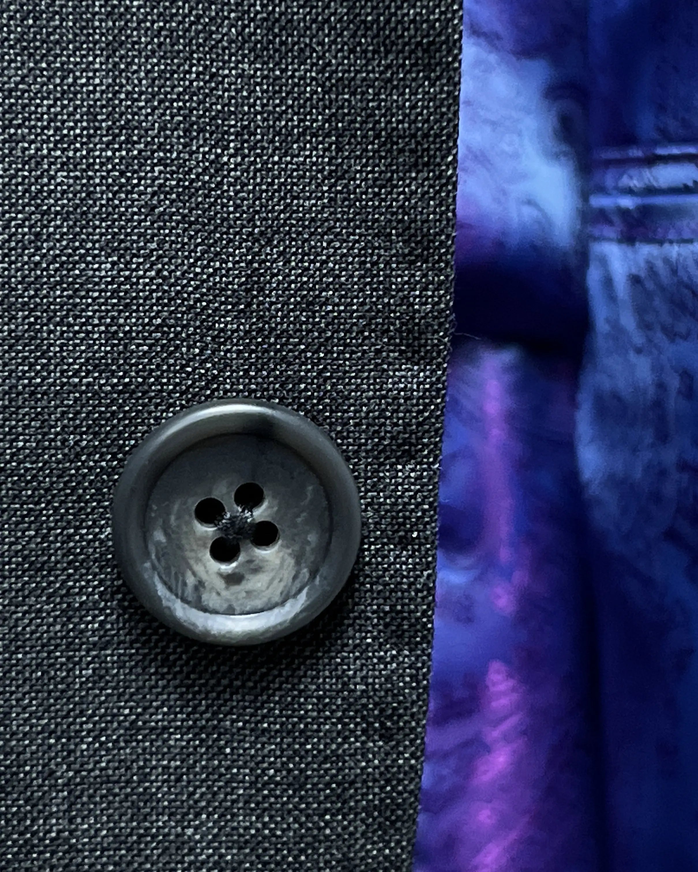 Button close up of medium grey sharkskin men's suit showing dark grey horn buttons