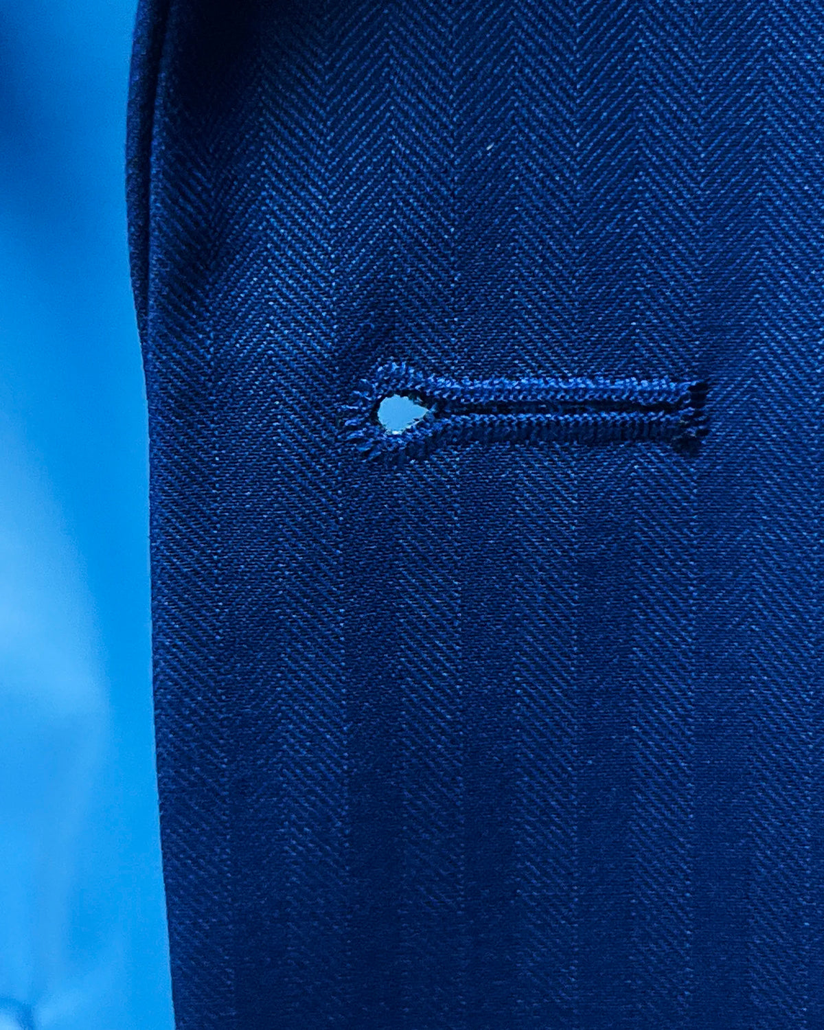 Buttonhole detail of royal blue herringbone men's suit showing tailored front buttonhole