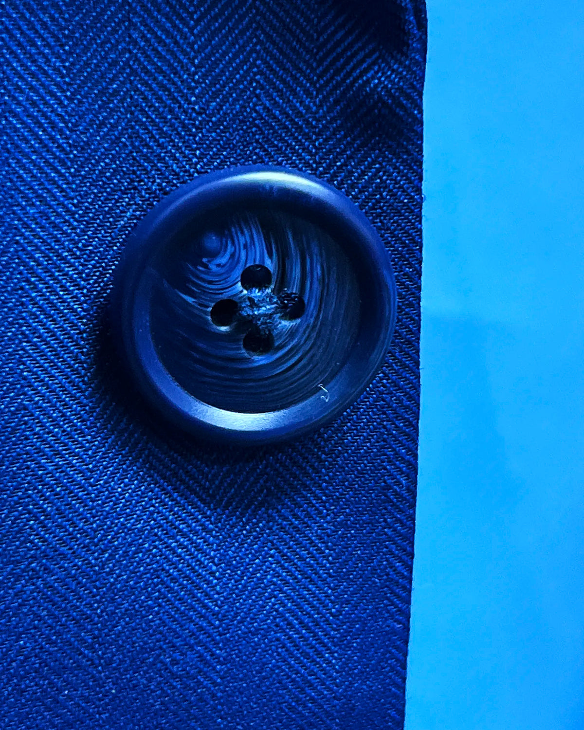Button detail of royal blue herringbone men's suit showing dark navy horn buttons