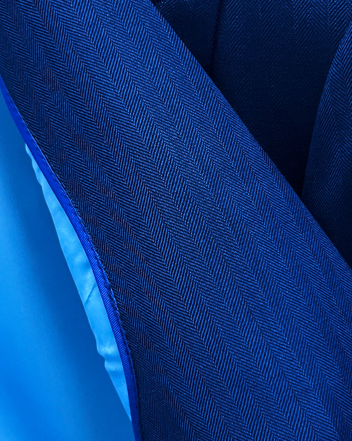 Fabric close up of royal blue herringbone men's suit showing fine self coloured herringbone texture