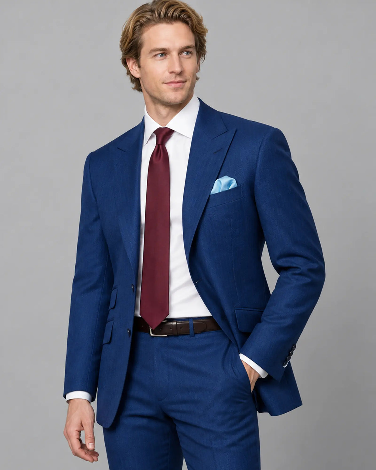 Three quarter model view of royal blue herringbone men's suit showing slanted flap pockets and ticket pocket
