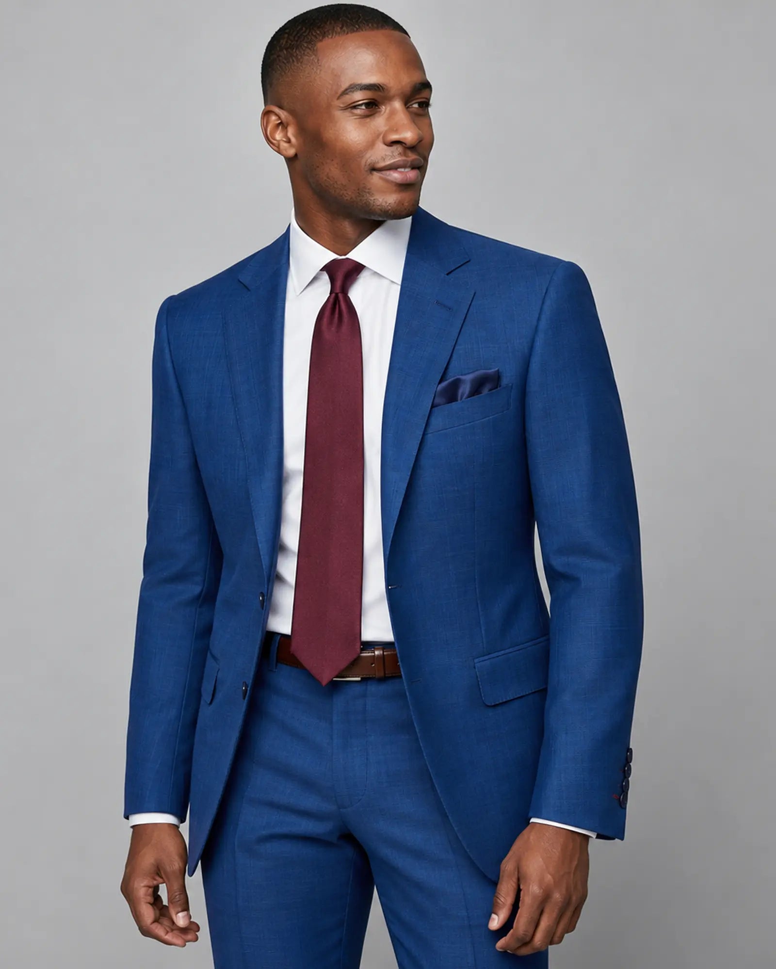 Mid thigh angled view of royal blue Prince of Wales glen check with rust overcheck men's suit showing the lapel and jacket shape