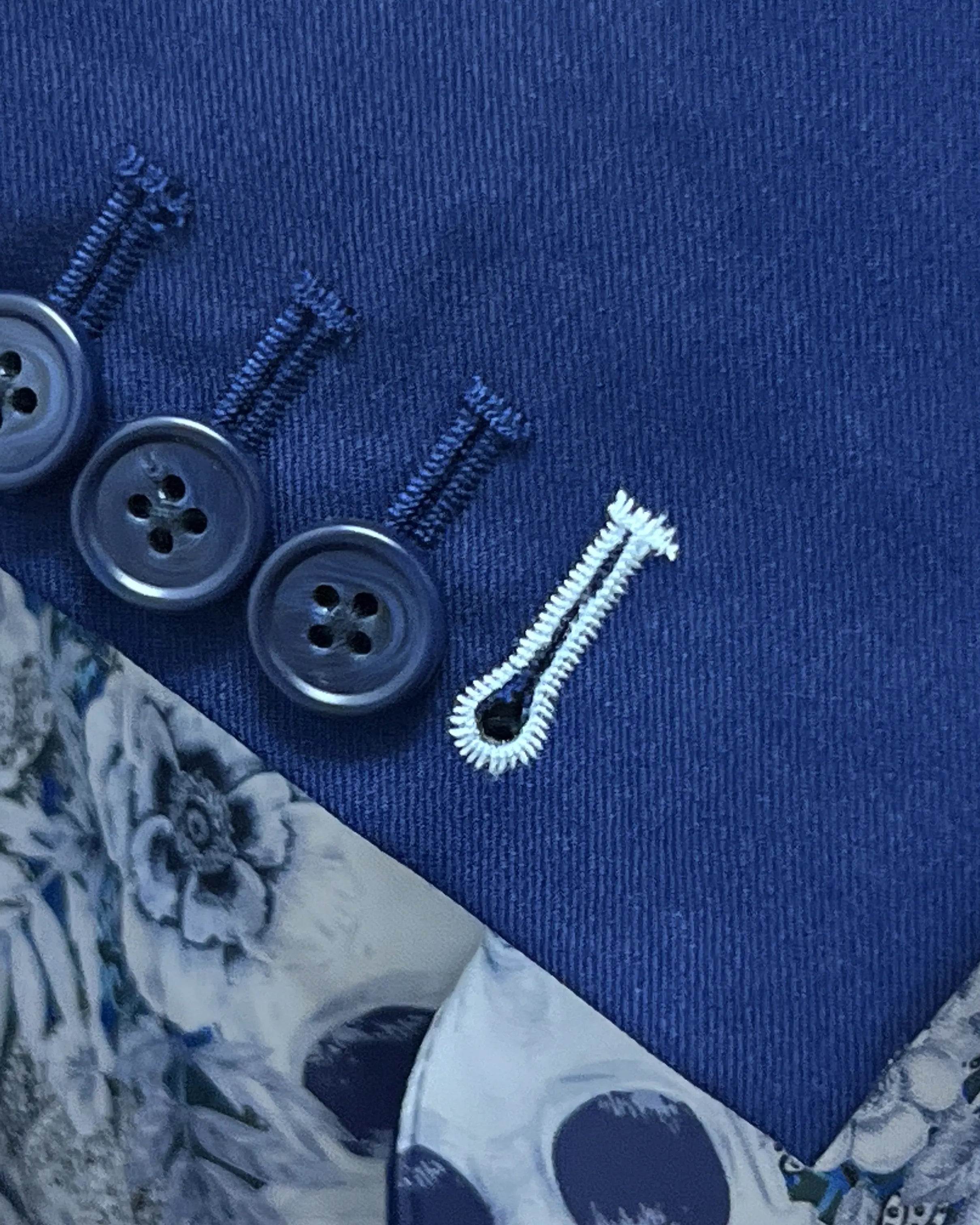 Sleeve cuff close up of royal blue sharkskin men's suit showing functional sleeve buttons with light blue contrast buttonhole thread.