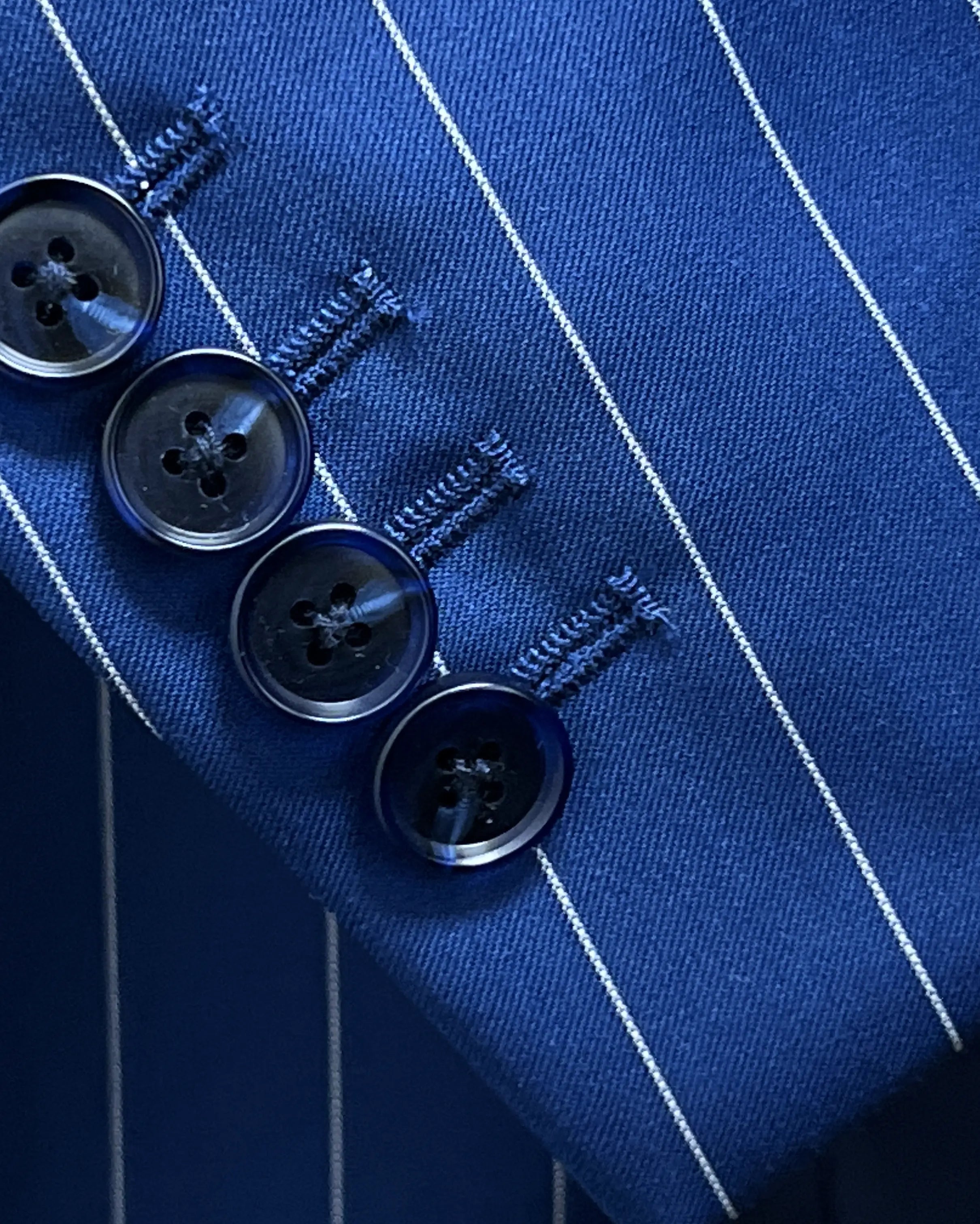 Sleeve close up of royal blue white pinstripes men's suit showing functional sleeve buttons