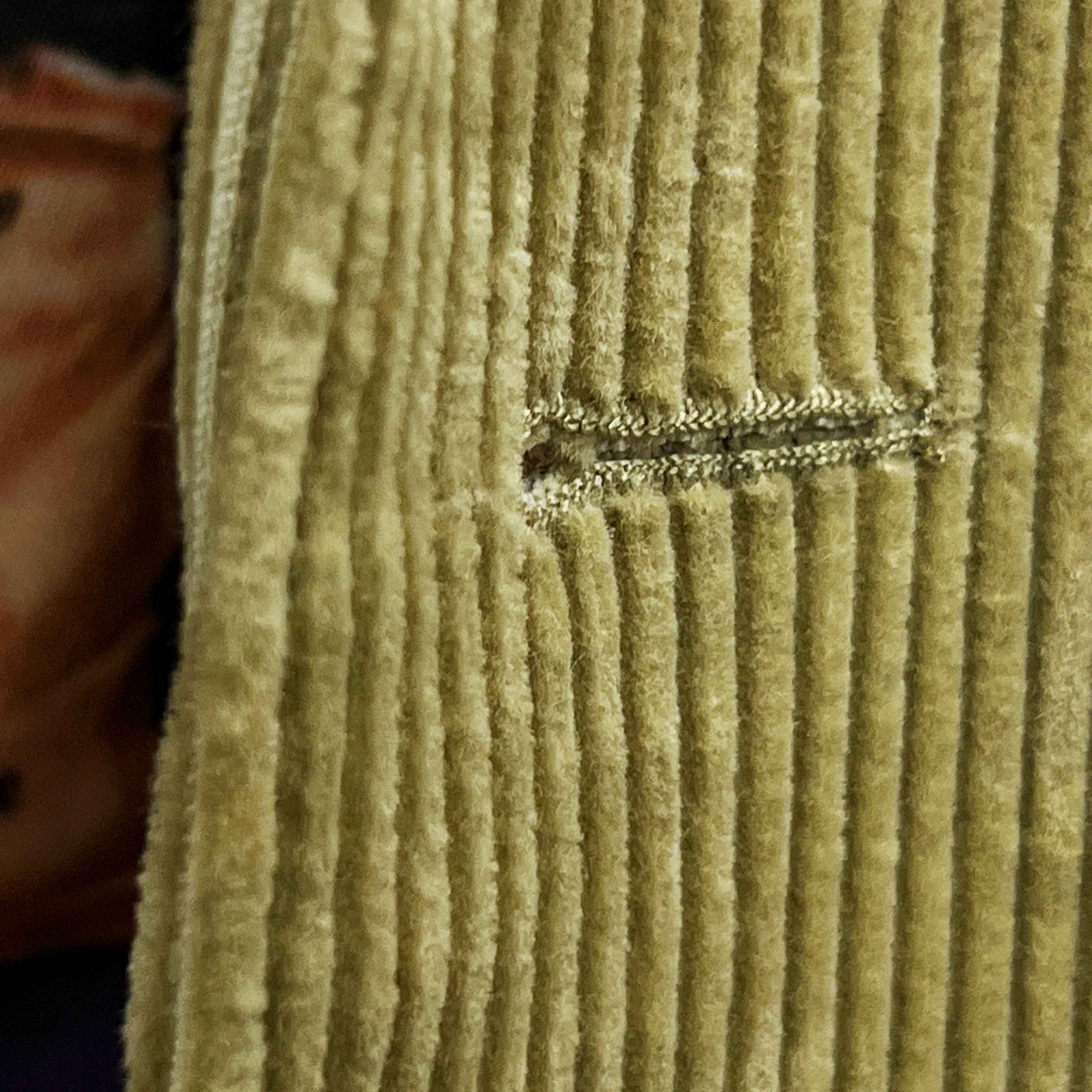 Detailed macro shot of hand-finished buttonhole stitching on tan corduroy sport coat with dark brown contrast thread
