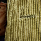 Detailed macro shot of hand-finished buttonhole stitching on tan corduroy sport coat with dark brown contrast thread