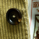 Close-up of chocolate brown horn buttons on tan corduroy sport coat showing natural marble-like patterns