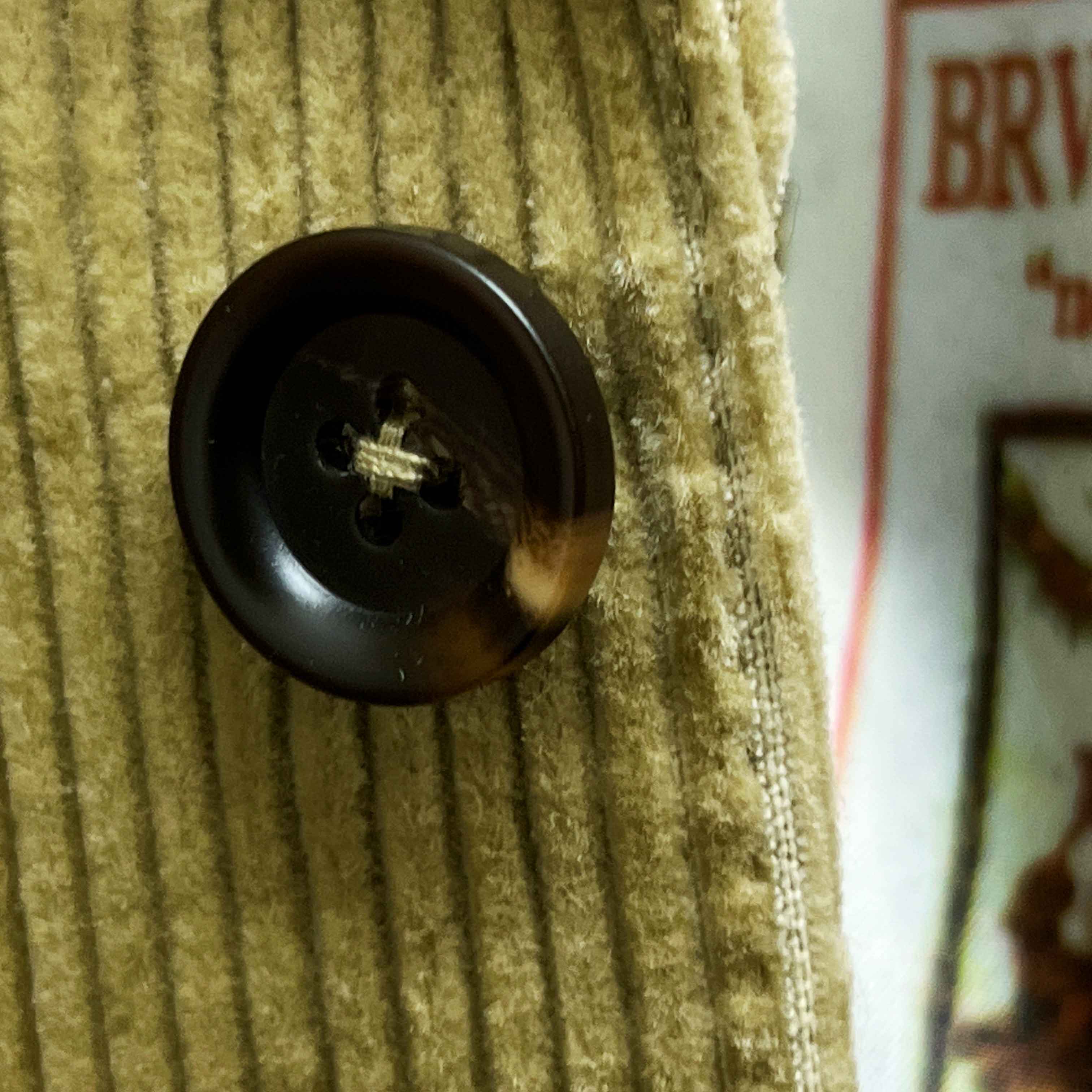 Close-up of chocolate brown horn buttons on tan corduroy sport coat showing natural marble-like patterns