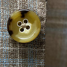 Close-up of tan and deep brown horn buttons on tan blue windowpane sport coat showing natural marble-like patterns