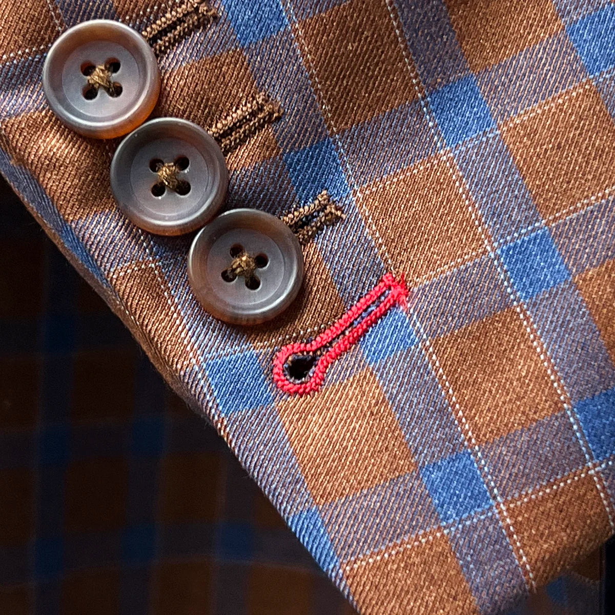 Working sleeve buttonholes with red contrast stitching demonstrating authentic custom tailoring and functional design elements