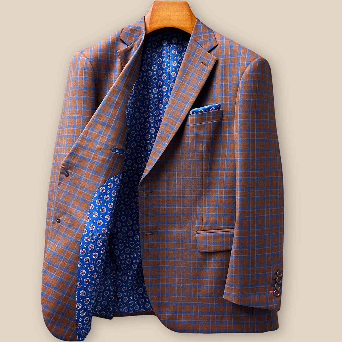 Detailed view of brown horn buttons against tobacco brown and cobalt blue check fabric showing natural texture and premium button selection