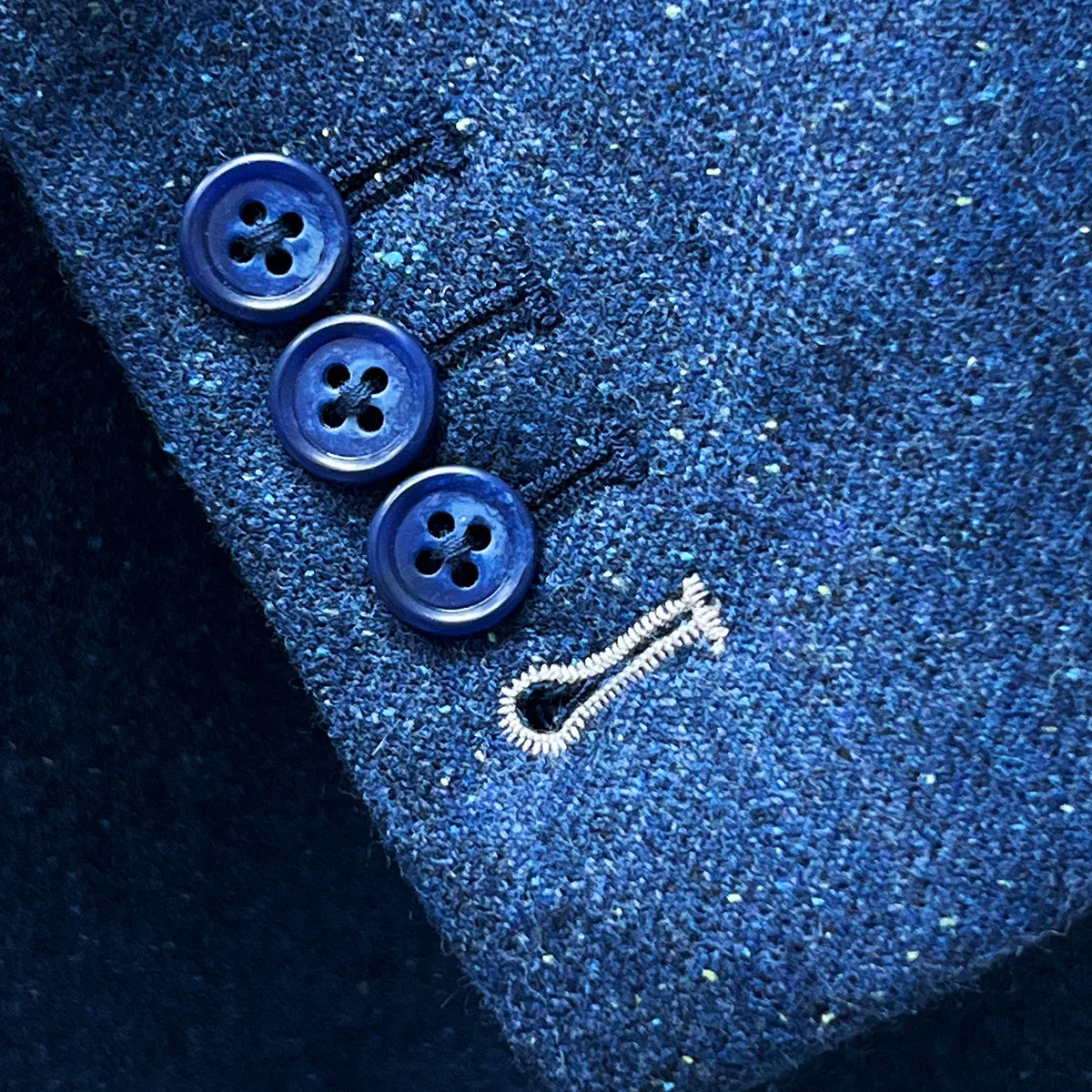 Close-up of functional sleeve buttons with silver accent buttonholes and pick stitching