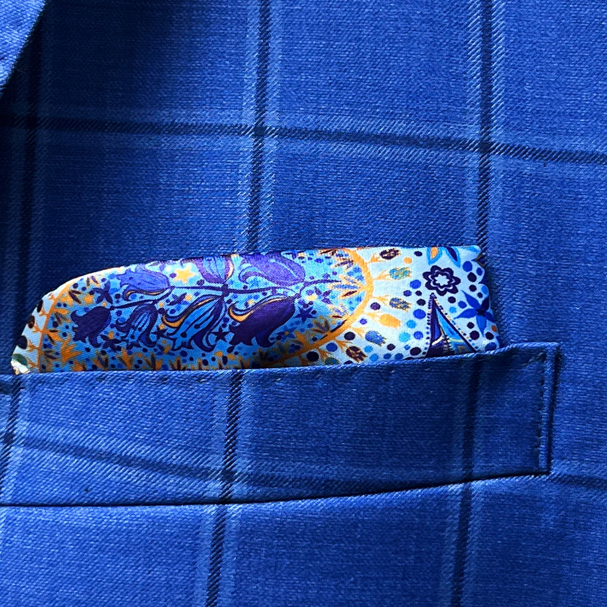 Breast pocket of royal blue windowpane suit jacket with built-in pocket square holder and hand-finished edges