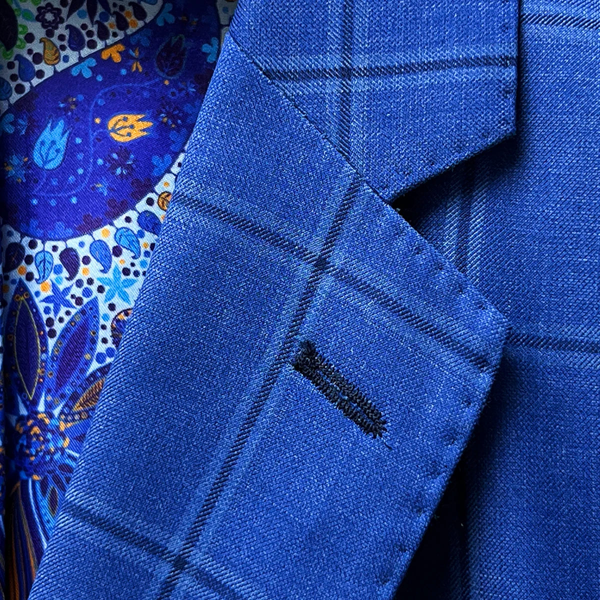Classic notch lapel detail on royal blue windowpane suit jacket showing hand pick stitching and navy check pattern