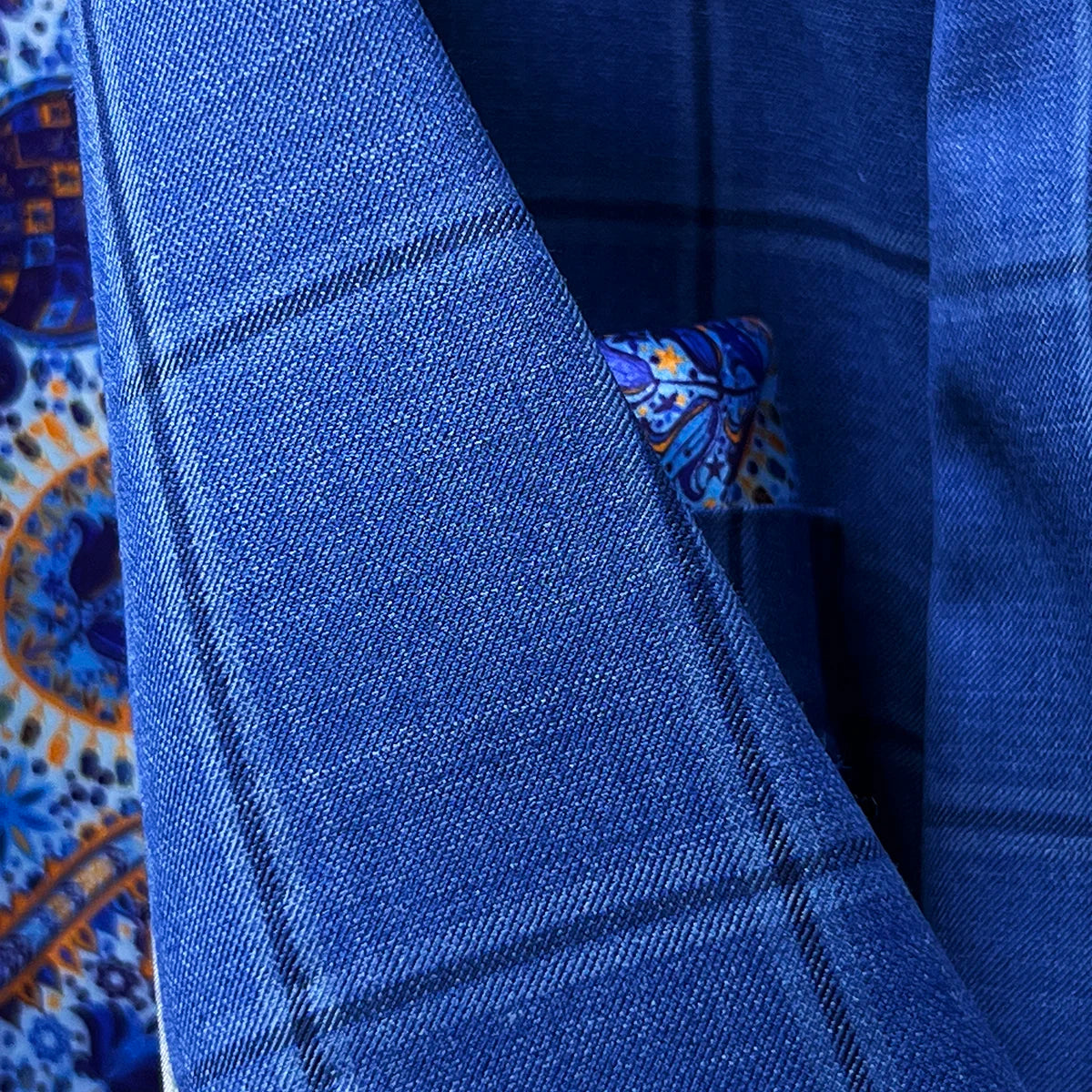 Contrast dark blue accent buttonholes on royal blue windowpane suit jacket sleeve showing precise hand-finished stitching